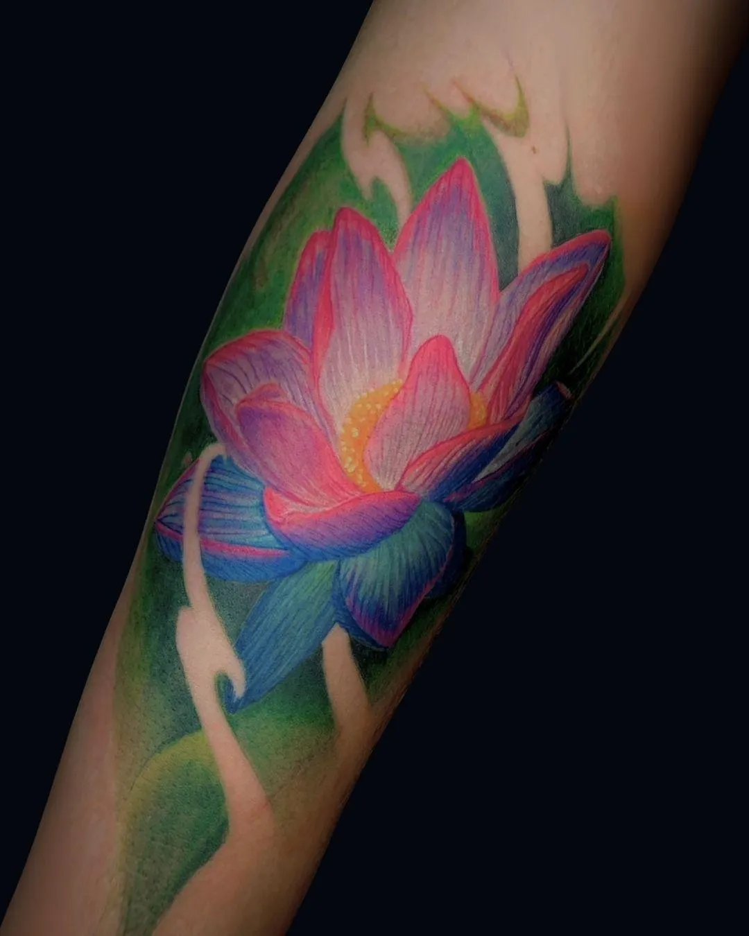 A vibrant color realism tattoo of lotus green background on the forearm done in Oceanside, California