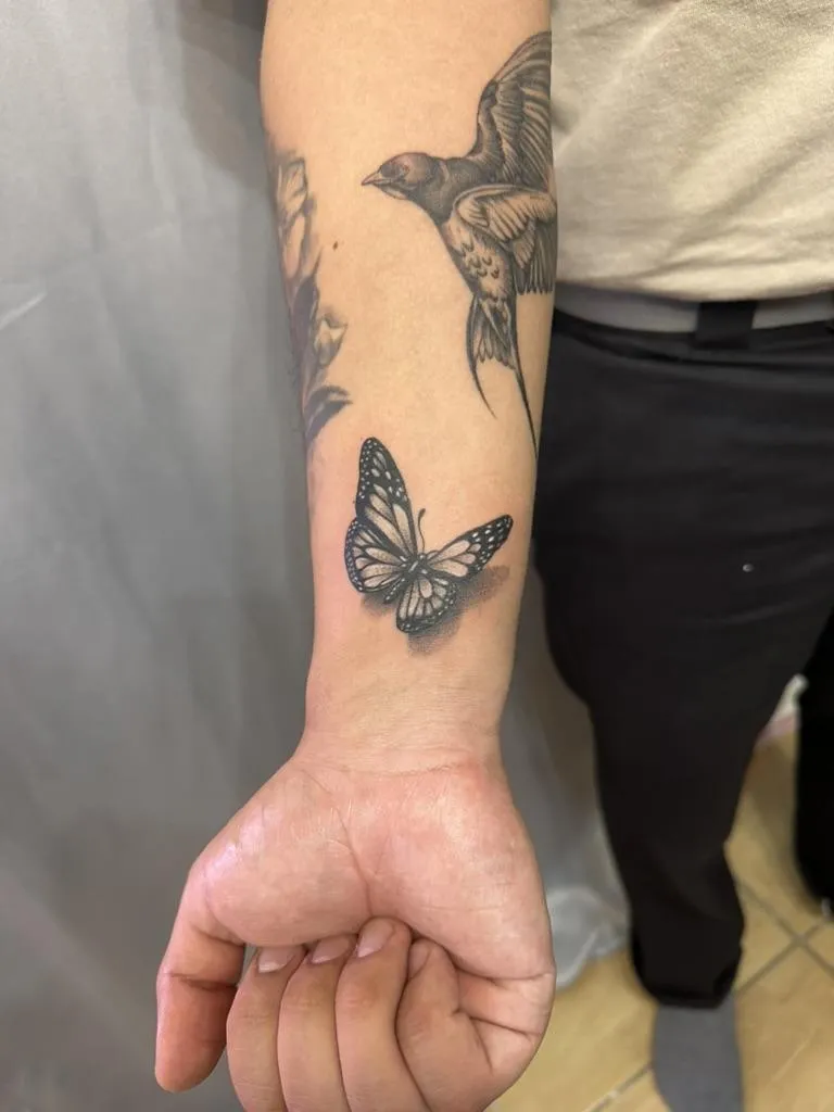 Black and gray realism tattoo of a butterfly on the forearm in Oceanside, California