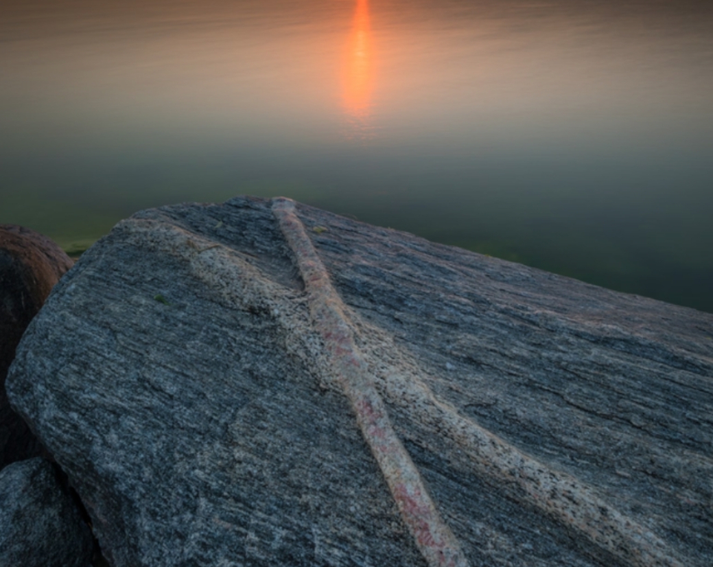 Hand holding burning incense stick with smoke rising.