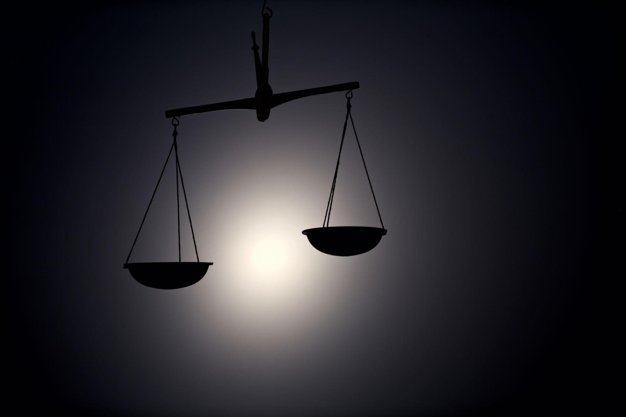 Hand holding burning incense stick with smoke rising.