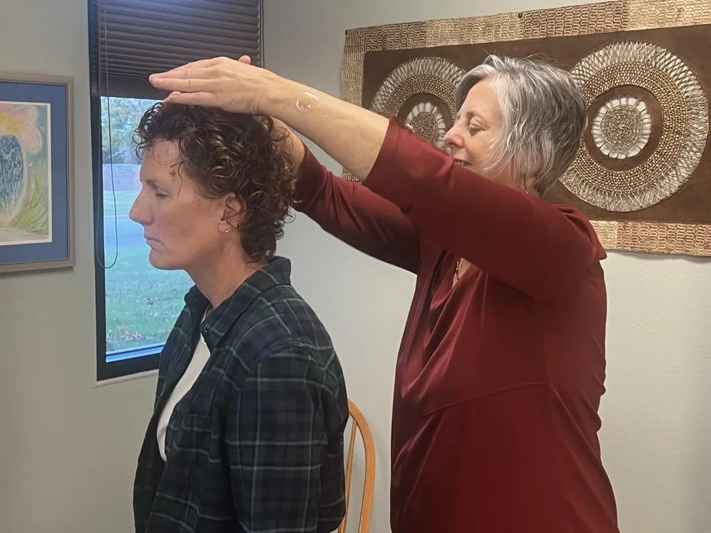 Practitioner adjusting gentle light panels while a relaxed client reclines in a calm wellness environment