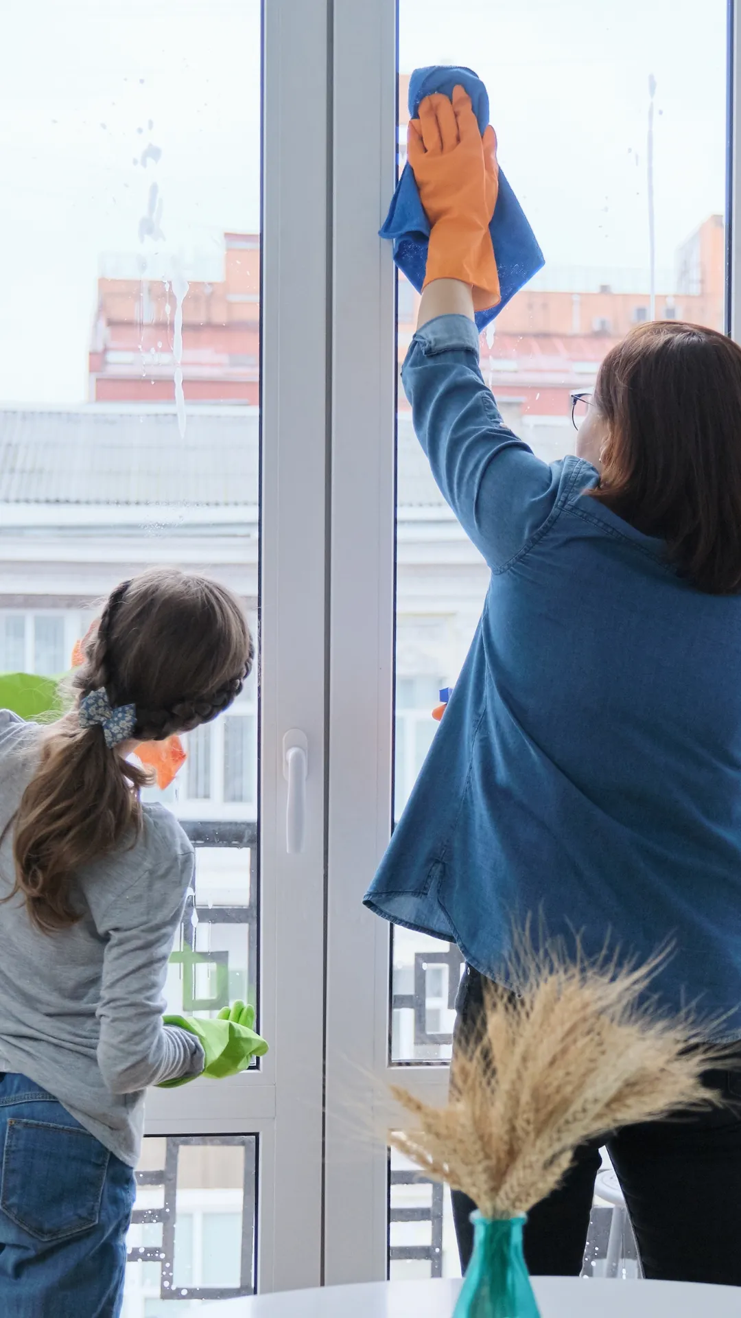 A professional cleaner and a young assistant cleaning the interior side of a window, demonstrating the thorough and detailed interior window cleaning services provided by Right Now Cleaning Services in Sydney.