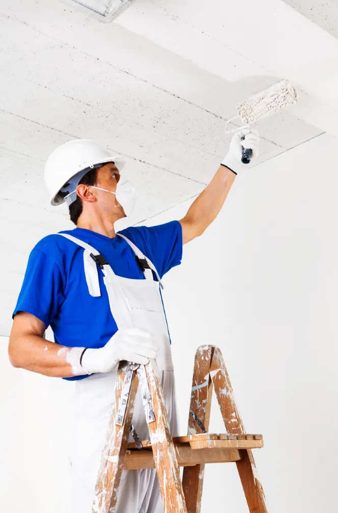 Professional painter on a ladder applying fresh paint to a ceiling, showcasing thorough and detailed painting services for end-of-lease requirements.