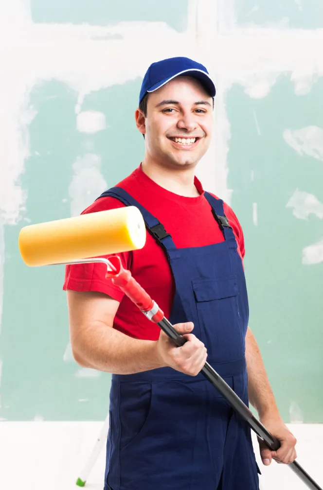 A professional house painter smiling while holding a paint roller, ready to provide top-quality painting services.