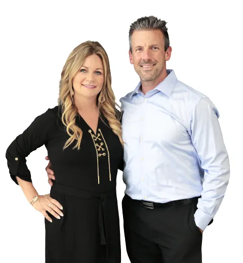 Jason and Jana DeLong of Heartland Homes KC, Kansas City real estate agents and AI-Certified Realtors, standing together in professional attire