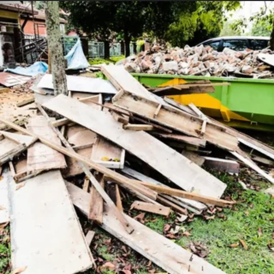 Yellow excavator clearing branches in a grassy field.