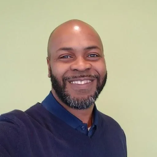 Chaka Ali, experienced life insurance consultant and founder of A.L.I. Creative Solutions | Wealth Builders Insurance Agency, smiling in a selfie headshot.