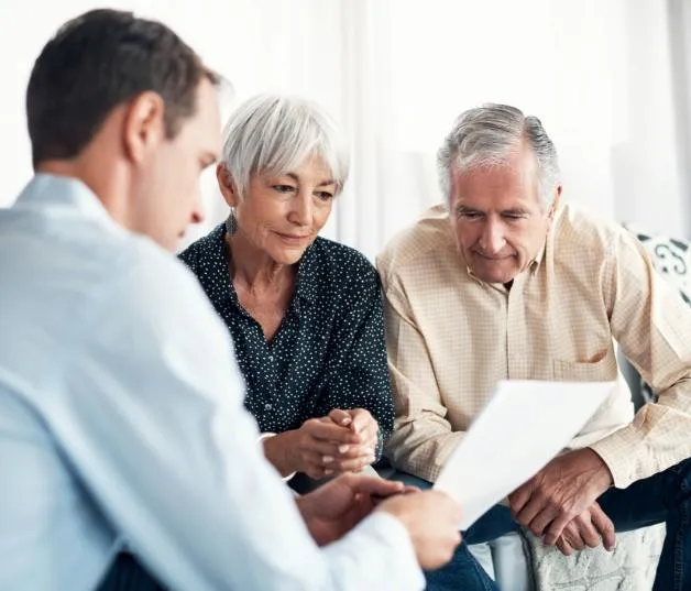 Insurance agent assisting senior couple, offering guidance on life insurance options for retirement planning and financial security.