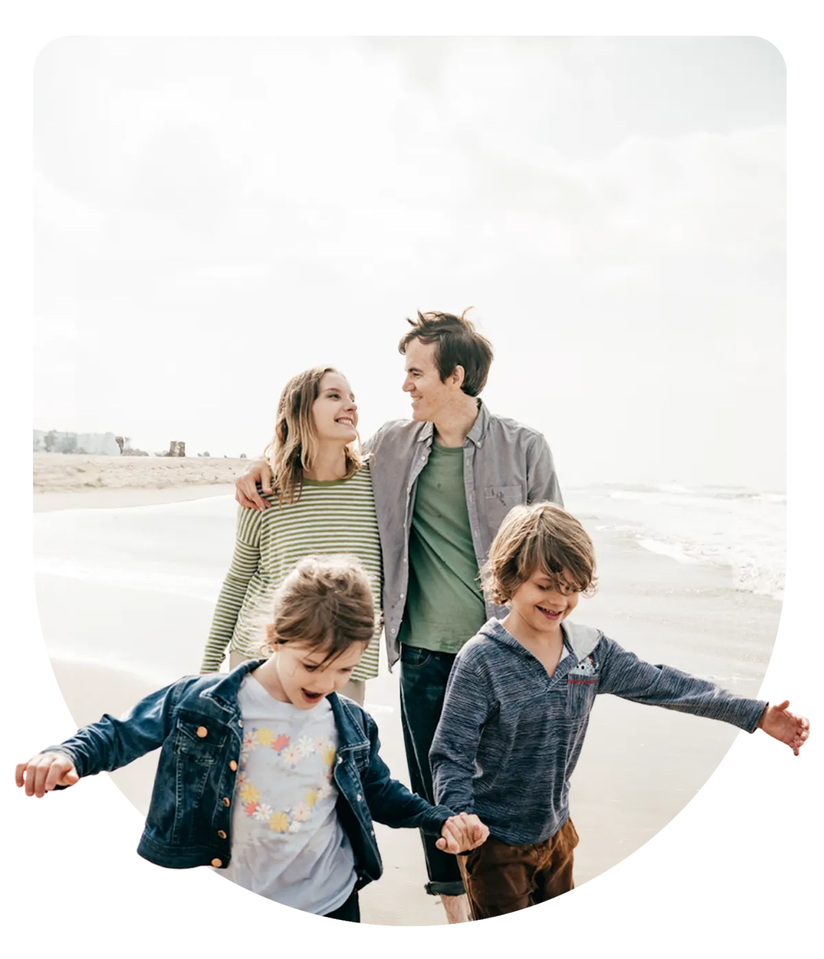 Young family walking and smiling together on a beach, representing happiness, health, and togetherness with ACA health insurance coverage.