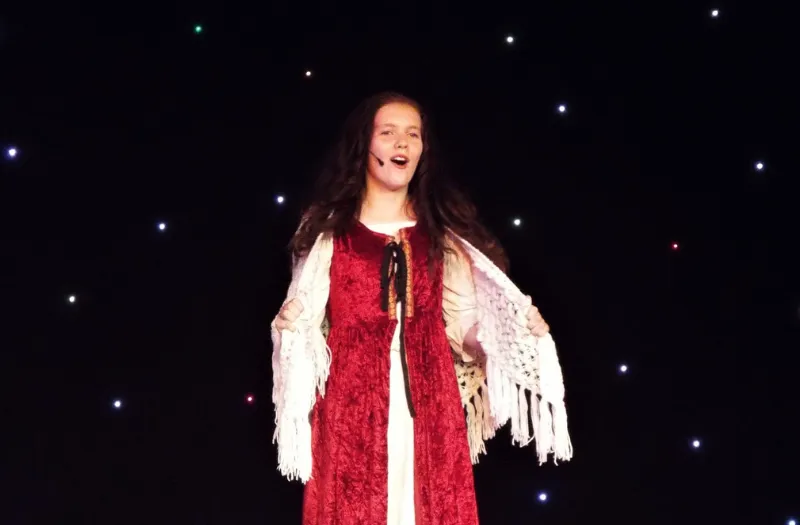 Young girl singing solo during a stage performance at Michelle Gauci Academy