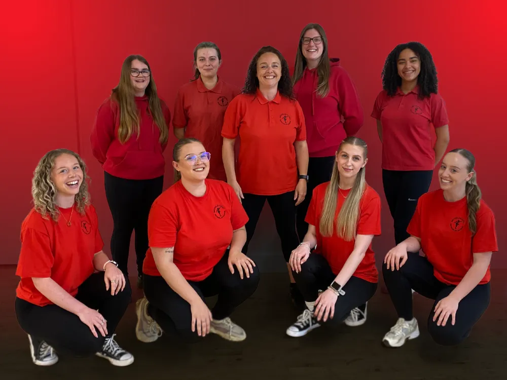 The Michelle Gauci Academy teaching team in red uniforms, dedicated to inspiring creativity and confidence in every child.