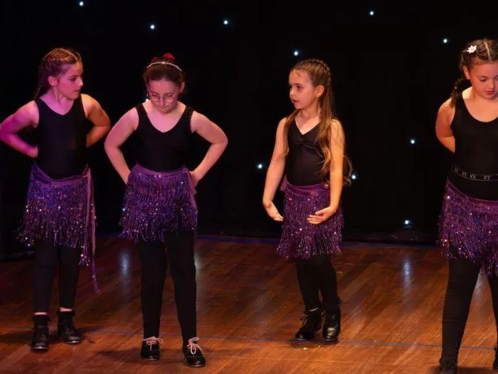 Young performers in sparkly purple costumes during Teeney Tap & Tap at the 2024 MGA show, showcasing confidence and rhythm.