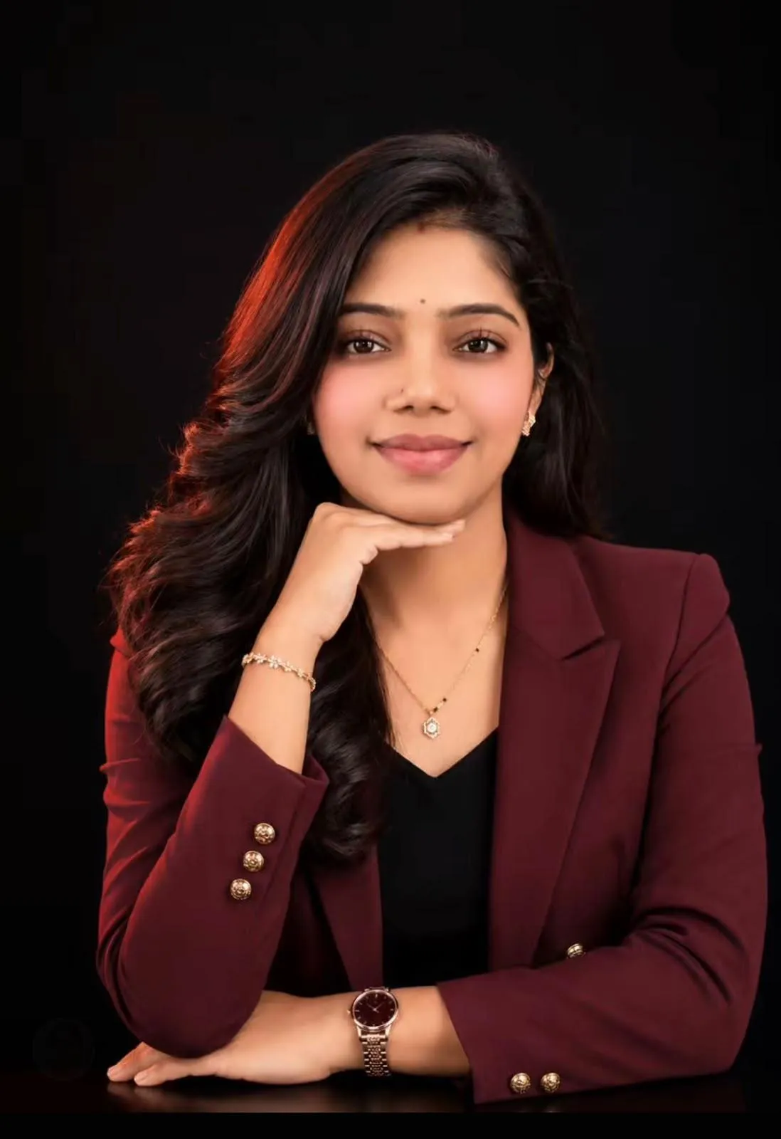 Professional head-and-shoulders portrait of an Indian woman in her thirties, smiling, in business clothing, against a LIGHT softly blurred background