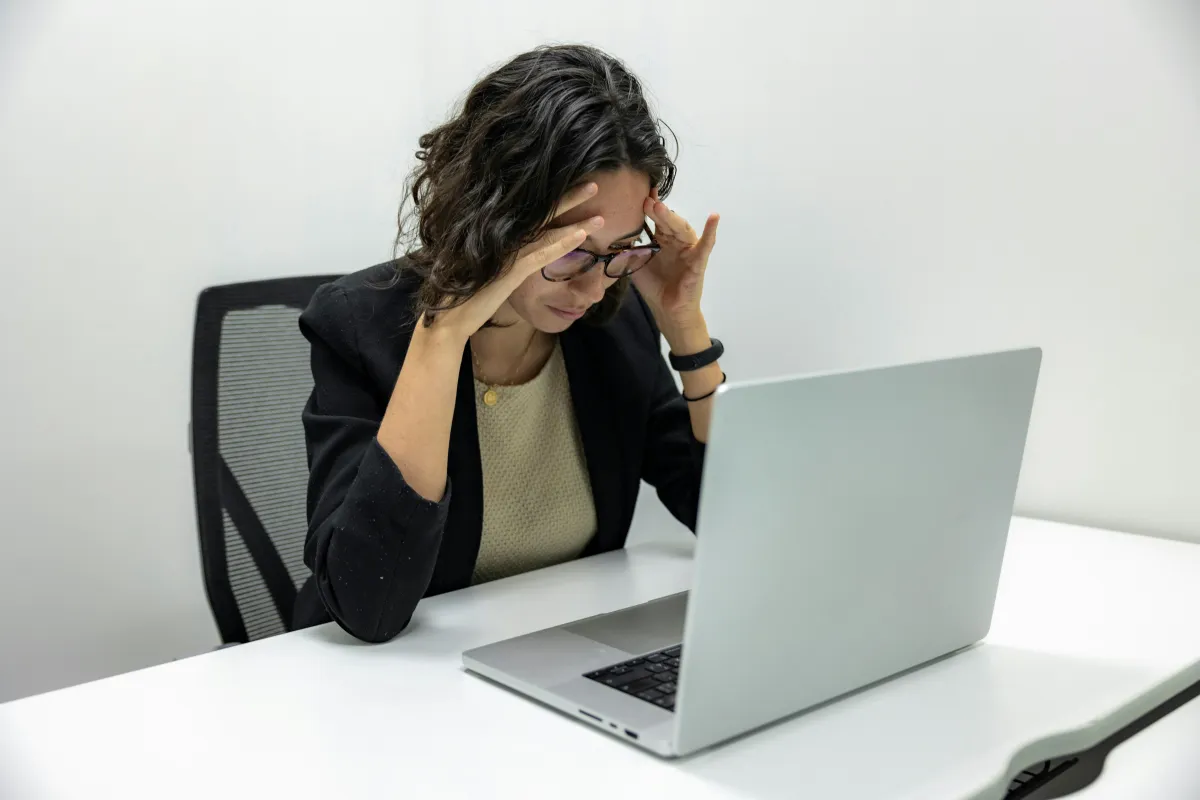 Frustrated business owner with head in hands at a laptop