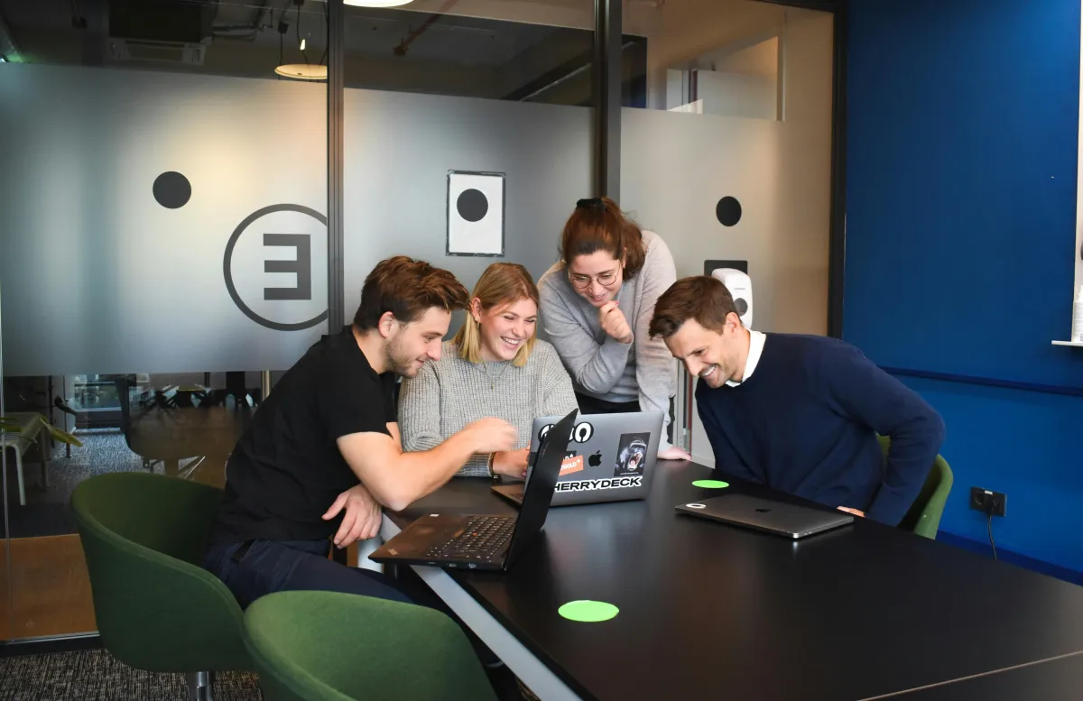 Small team collaborating around a laptop in an office