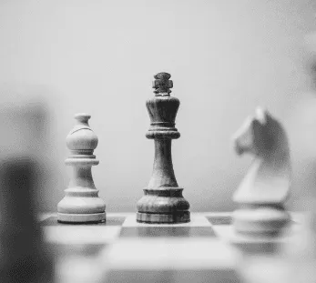 Schwarz-weiß-Foto eines Schachbretts mit Fokus auf König, Läufer und Springer – symbolisch für Strategie und Planung.