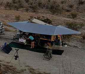 Campsite setup with a large canopy and outdoor gear in the desert.
