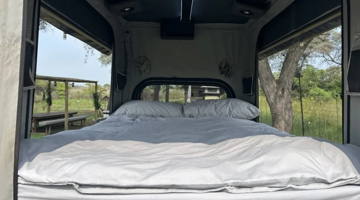 Interior view of a pop-up camper bed with windows open.