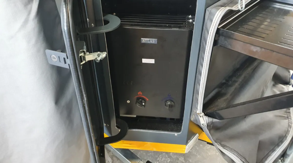 Camping trailer with a large awning set up beside a pond.