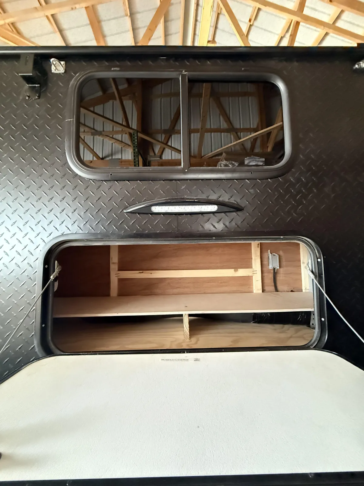 Riptide camper rear exterior showing barn door opening and storage shelf inside