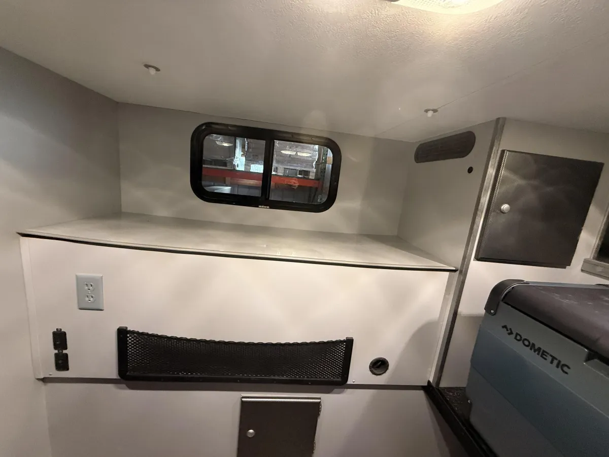 Riptide camper interior showing rear cabinet storage, sliding window, and Dometic fridge space
