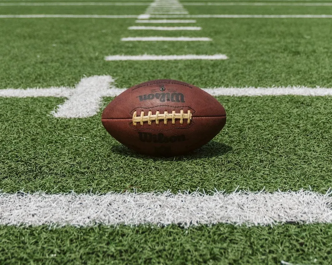 DCCS - nfl styled football sitting on a green football field.