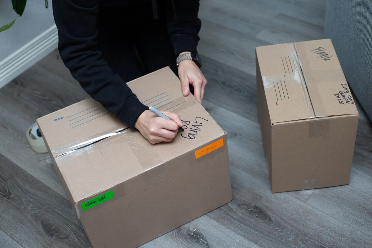 Photo of Morgan the owner labeling a box that she packed