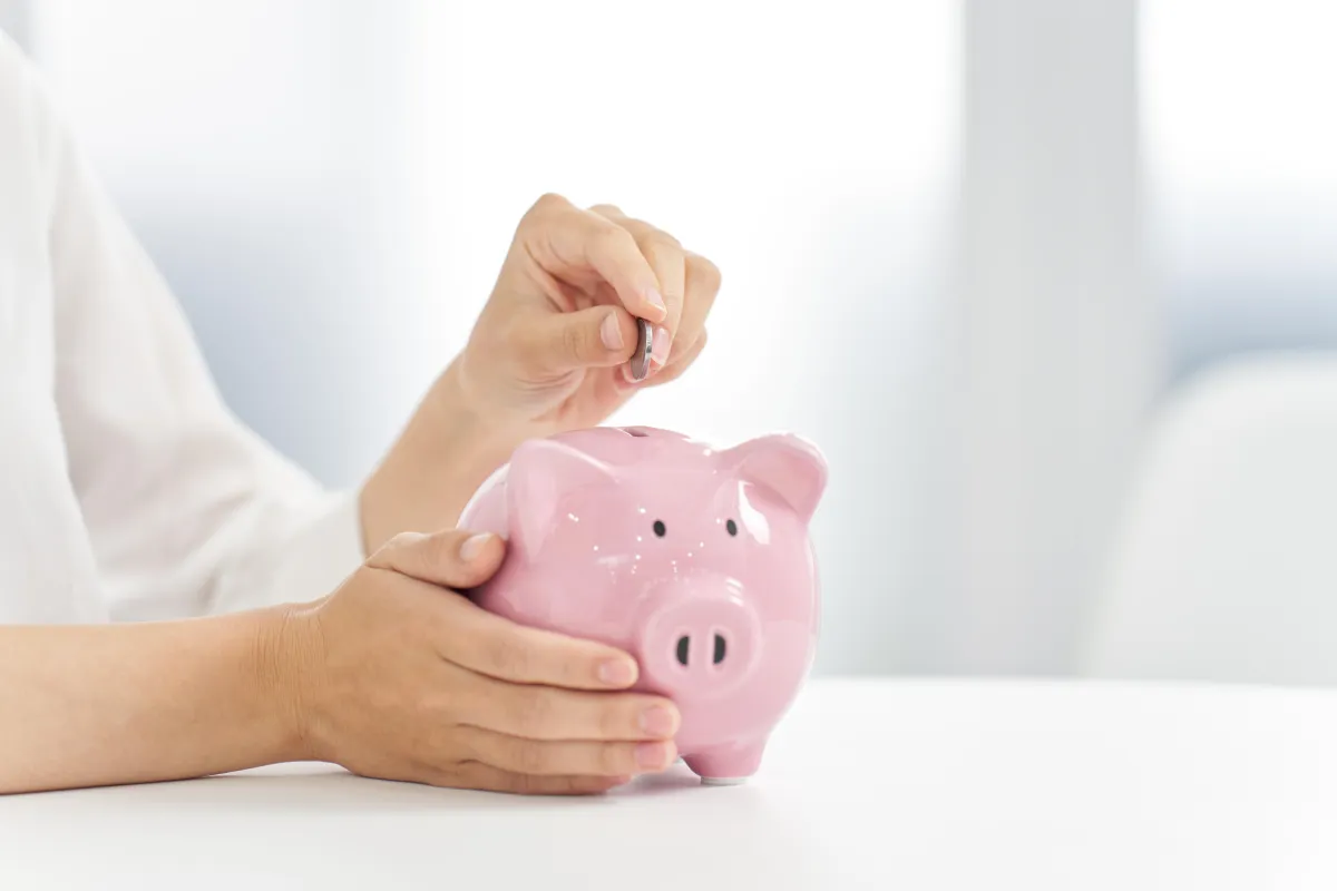 woman putting coins into a piggy bank
