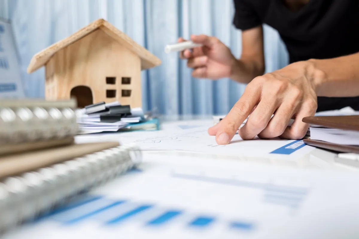 wooden house and paperwork with person looking over it 