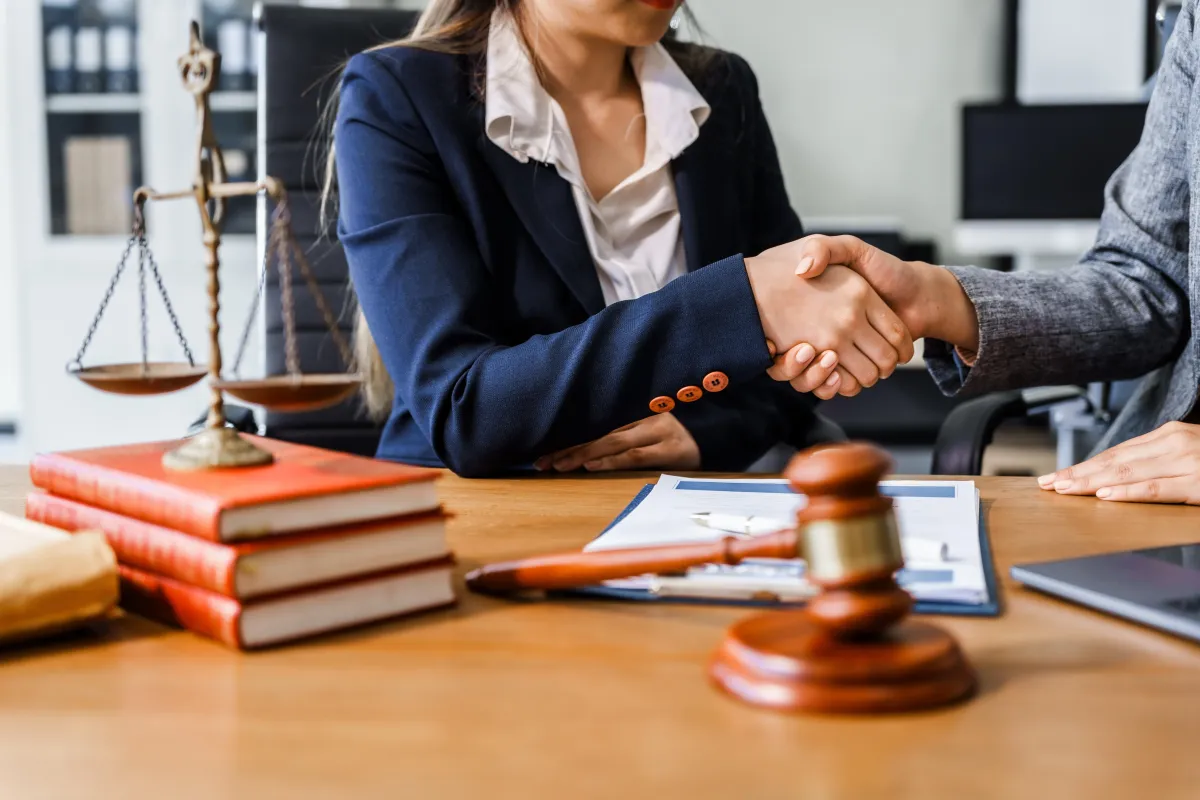 two people shaking hands behind a gavel 
