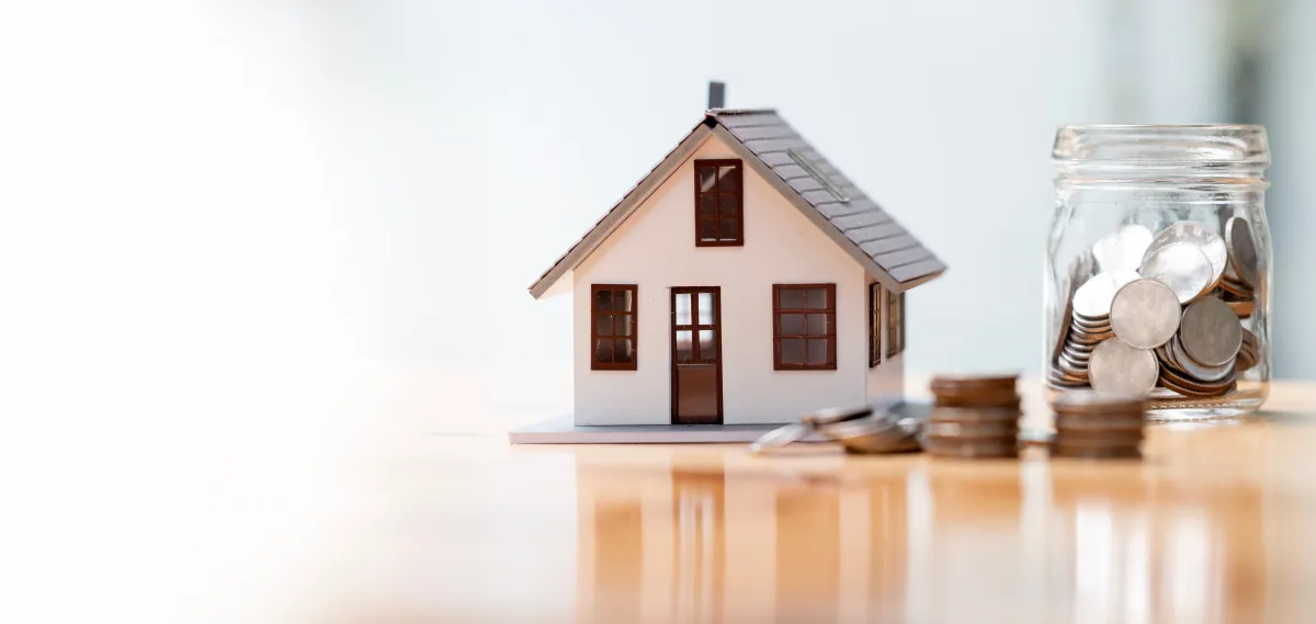 toy house next to a glass jar full of coins 