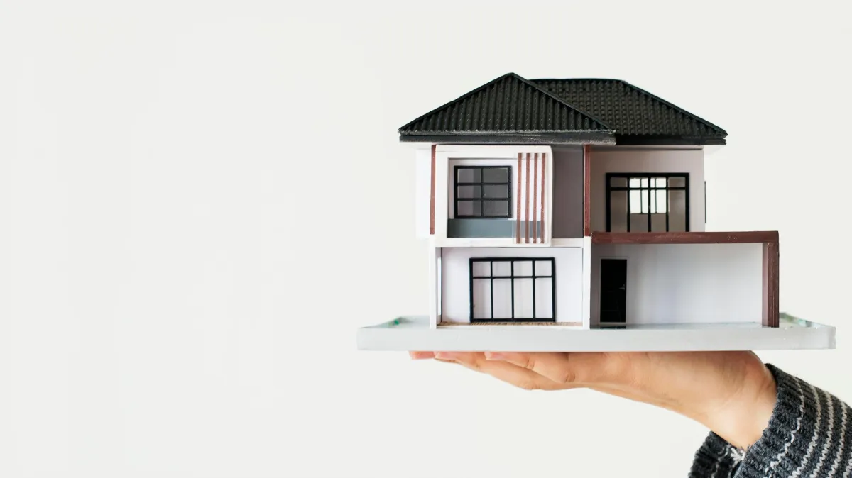 hand holding up model house