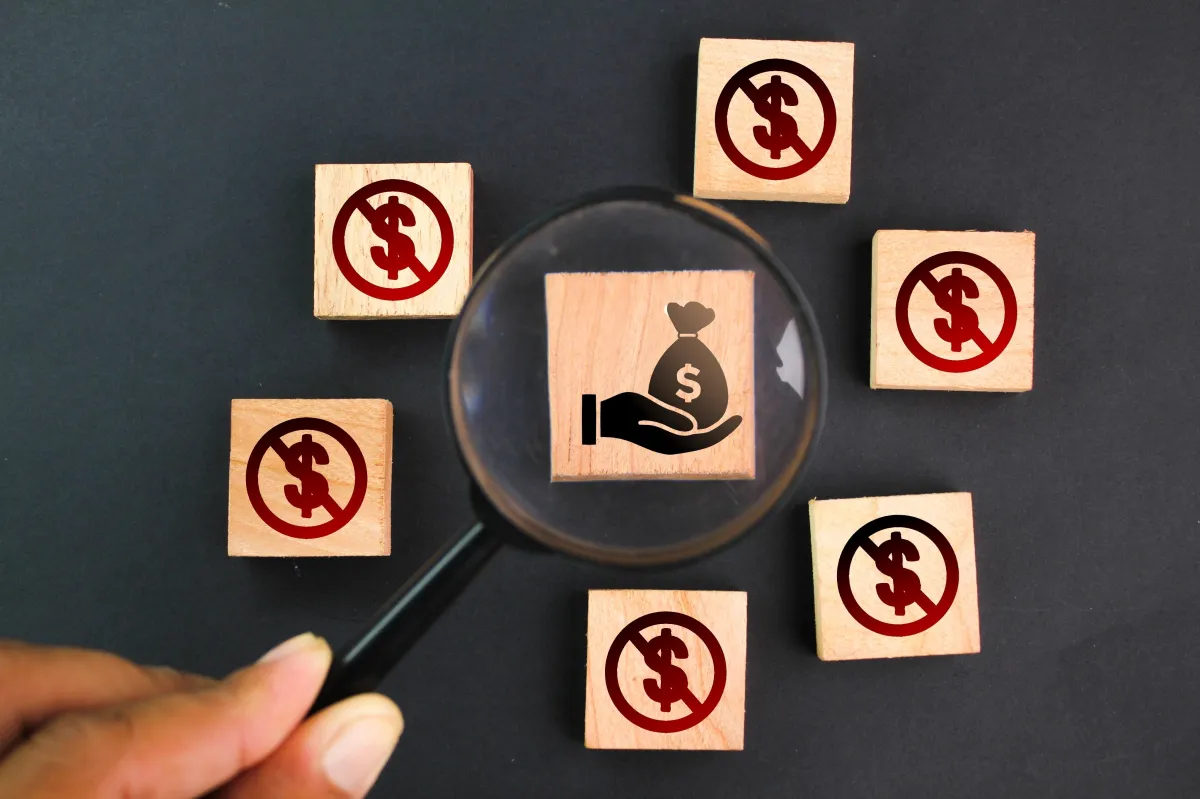magnifying glass over wooden block with money sign