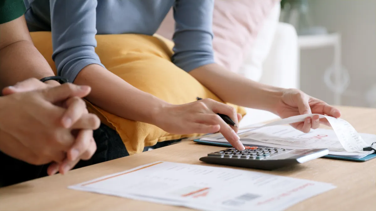 two people with calculator and papers on table