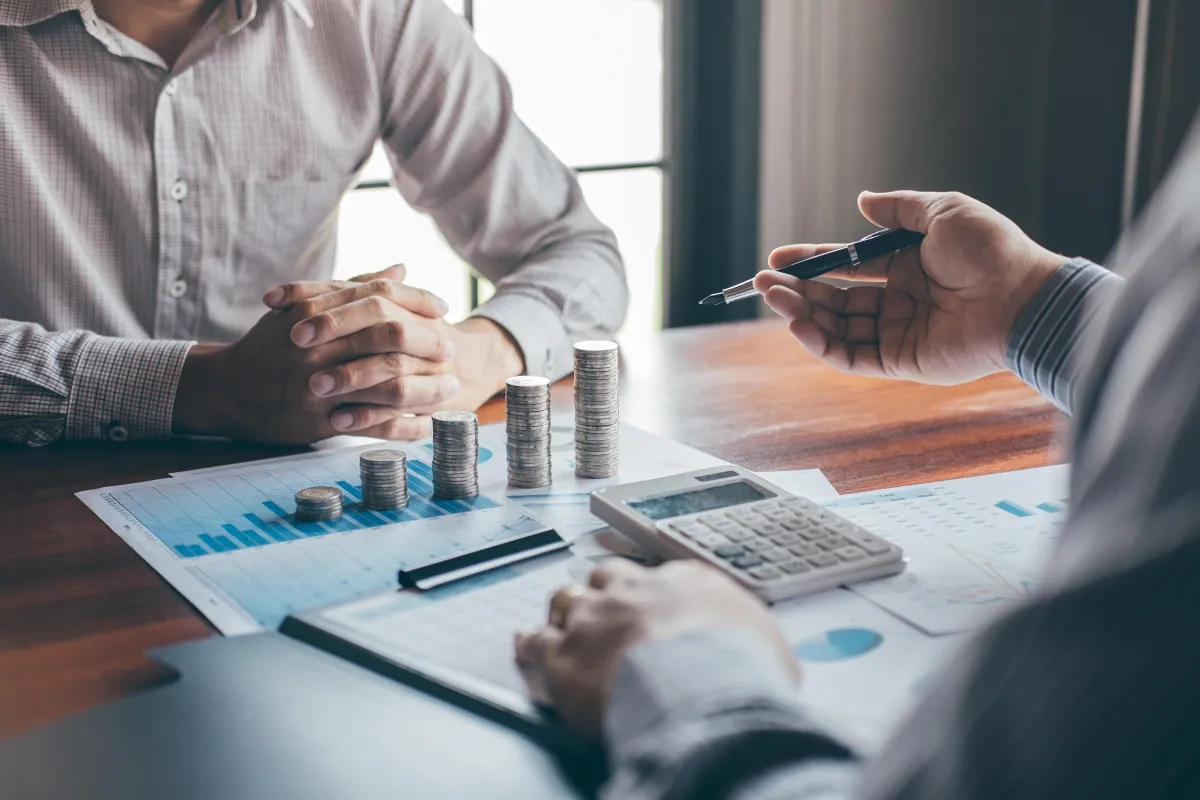 two men looking at stacks of coins and paperwork