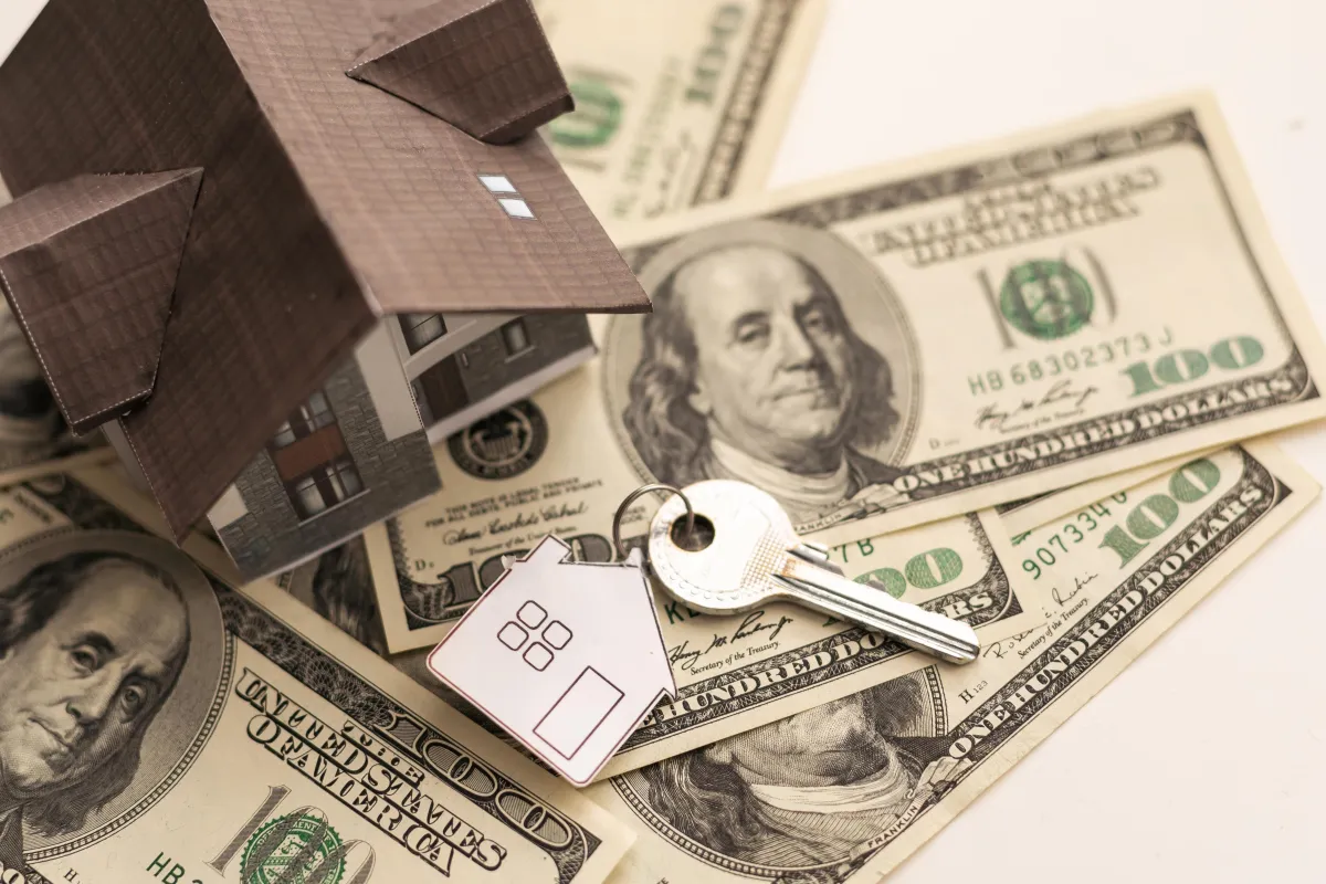 money with toy house and key on top