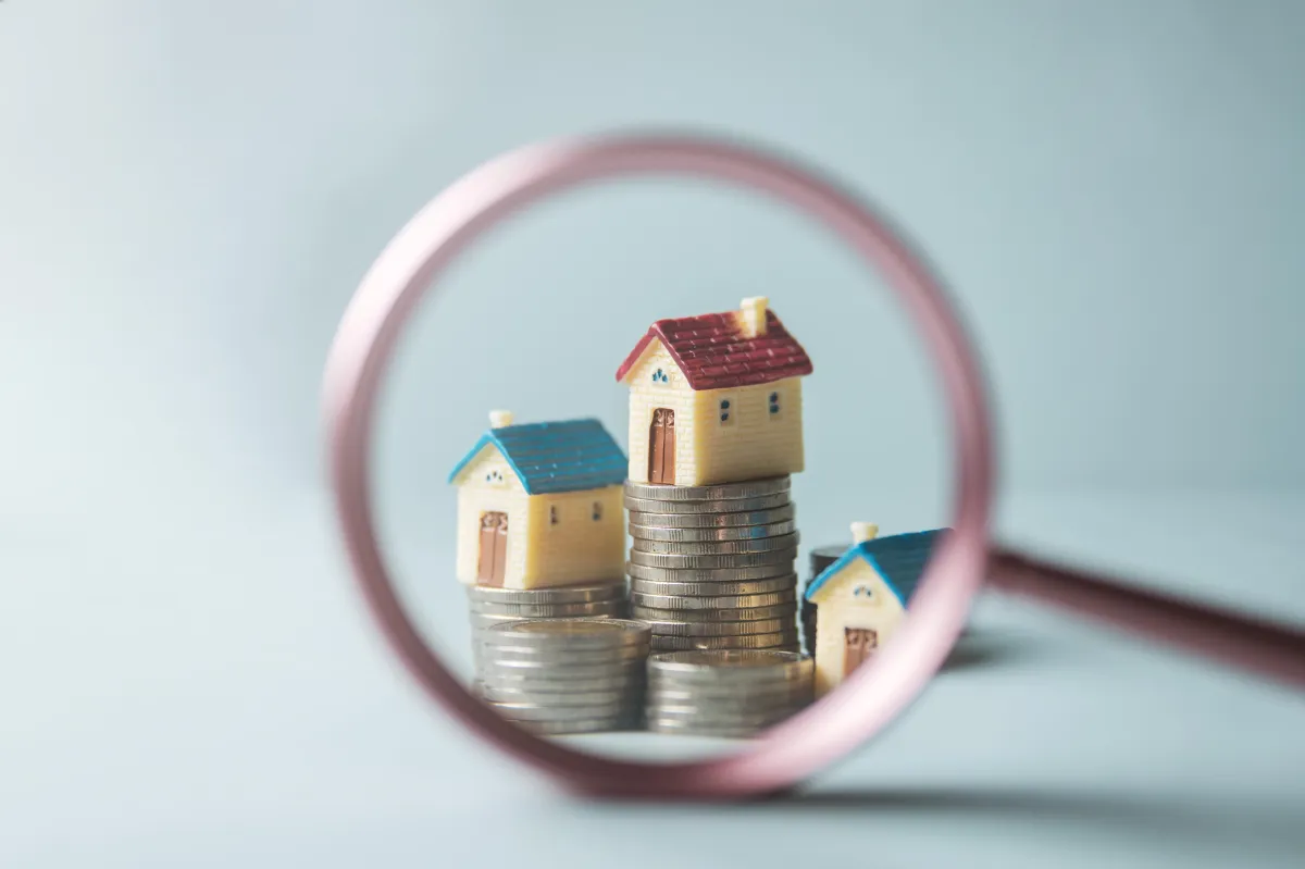 magnifying glass over houses and coins