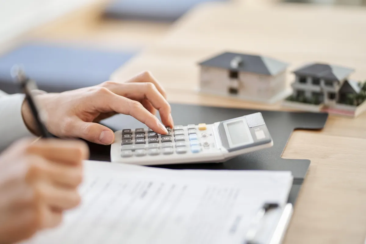 man typing on calculator and writing on papers