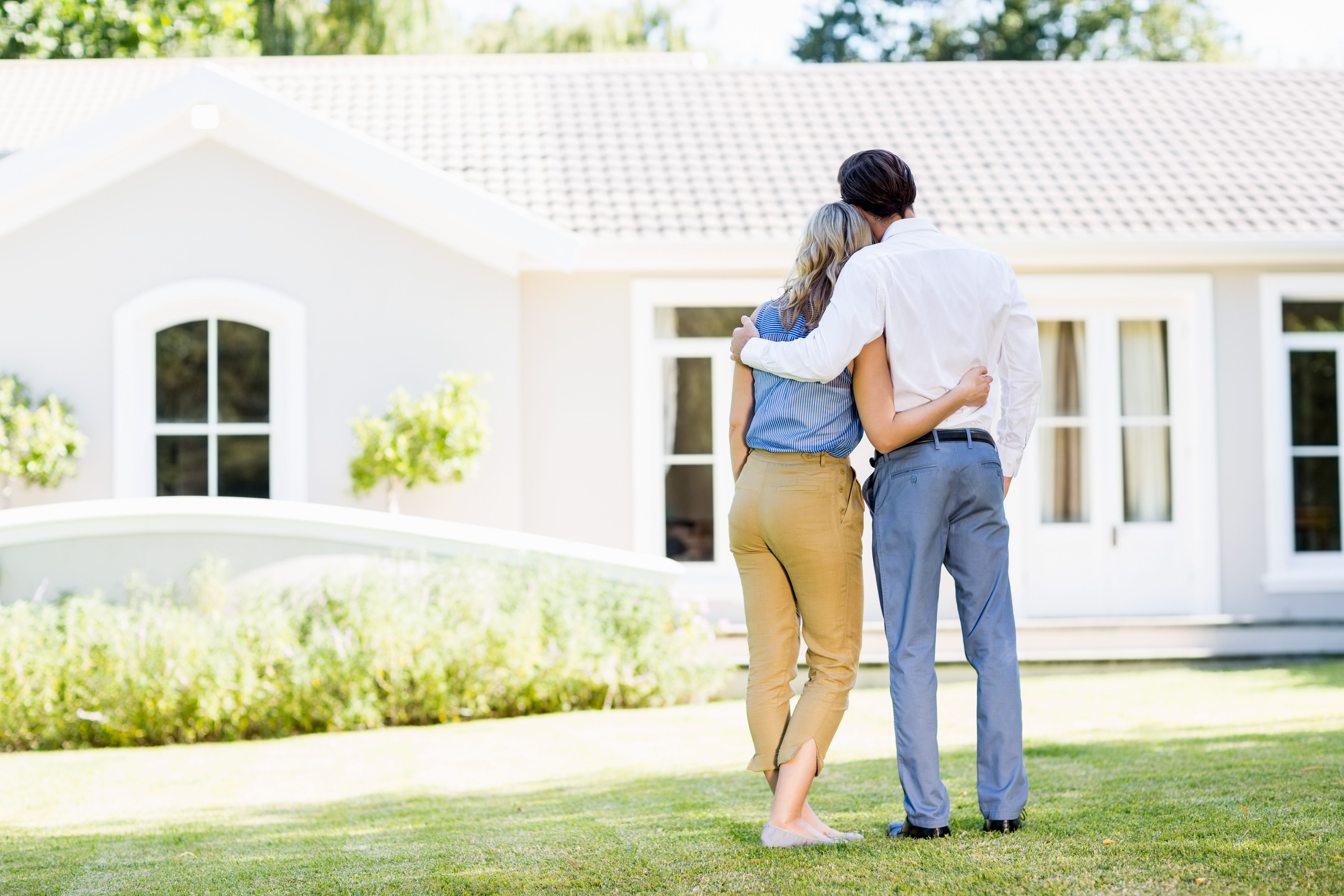 couple hugging in front of house