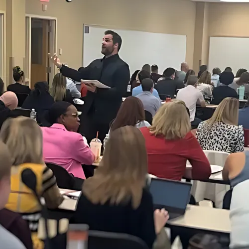 Kyle Evans delivering a keynote presentation to a room of engaged business professionals.