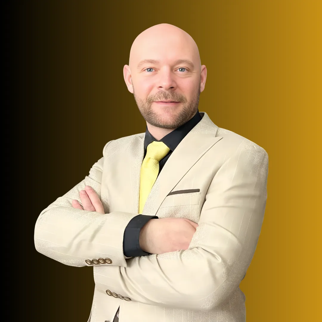 Baz Porter who confident bald man with a neatly trimmed beard, dressed in a stylish beige suit, black shirt, and yellow tie, standing with arms crossed against a gradient black and gold background. His poised and professional demeanor reflects his expertise and assertive leadership style.