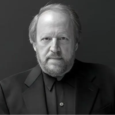 A professional black-and-white portrait of Dan Silberberg with a serious and confident expression. He is wearing a dark suit against a plain dark background, exuding authority and depth. This image is used for a testimonial, highlighting trust, experience, and leadership.