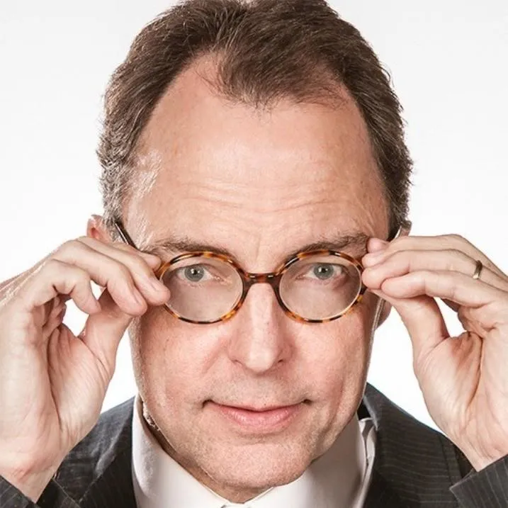 A professional portrait of Frank King adjusting his glasses with a confident expression. The close-up highlights his thoughtful demeanor, wearing a suit against a plain white background, emphasizing professionalism and insight. This image accompanies a testimonial, suggesting expertise, credibility, and trustworthiness.