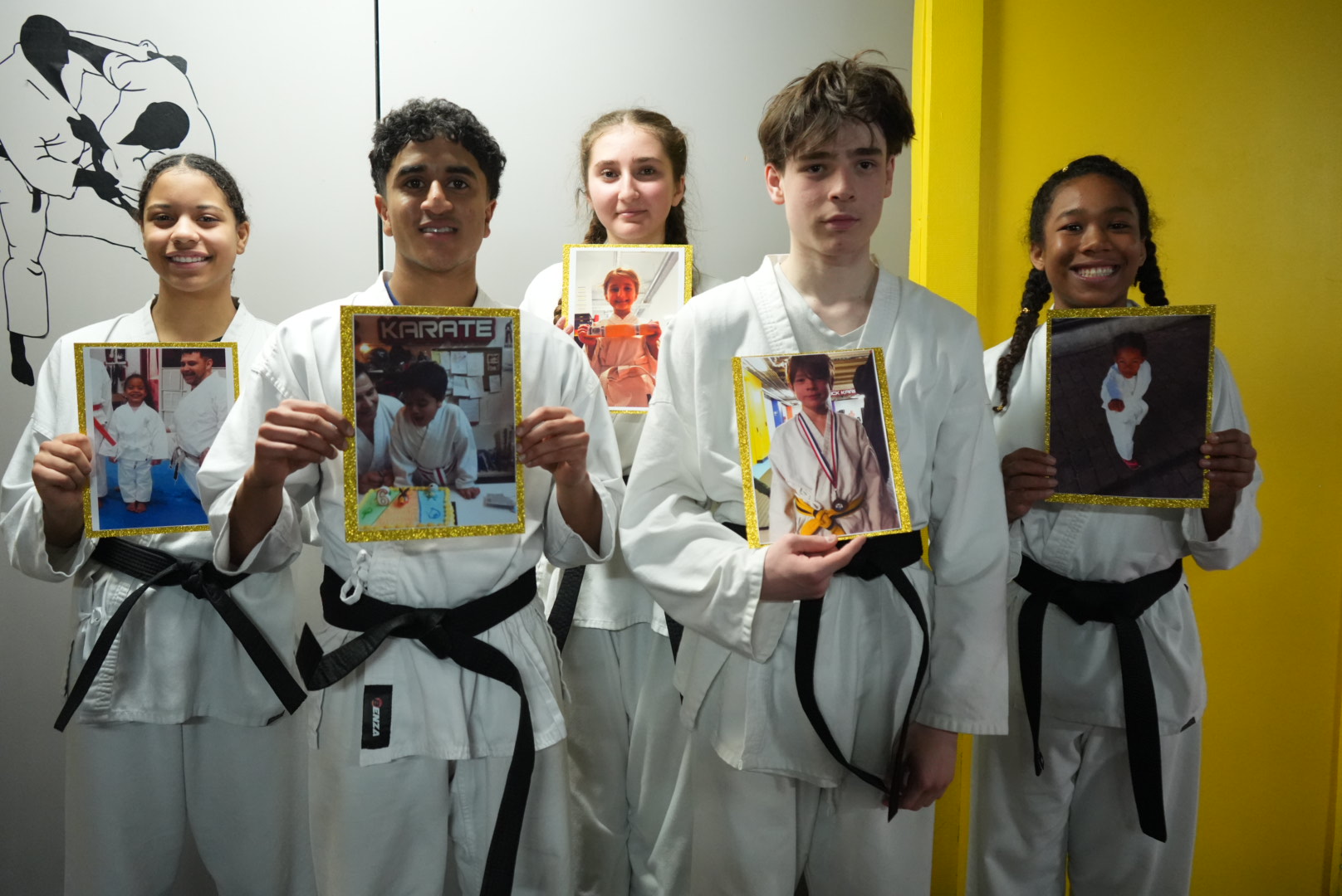 Students holding their first-day photos in the dojo