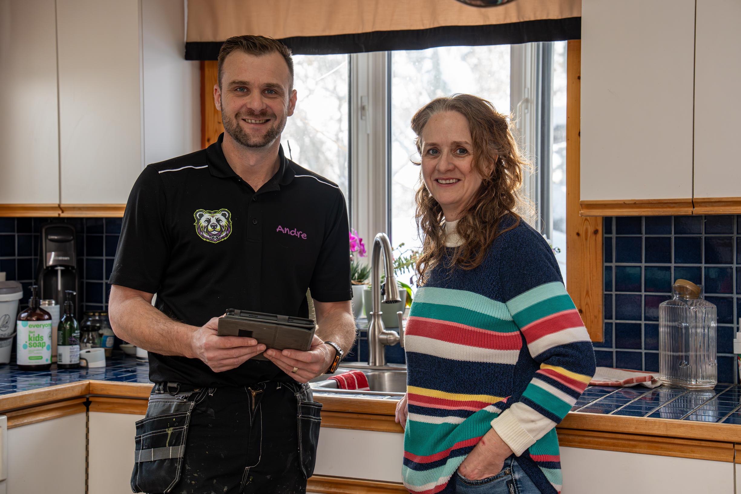 Plumbing talking to woman in kitchen. 
