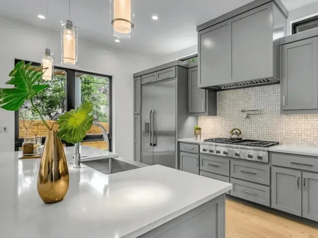 Modern Richmond, VA kitchen with navy blue cabinets, quartz countertops, stainless steel appliances, hardwood floors, and large windows.