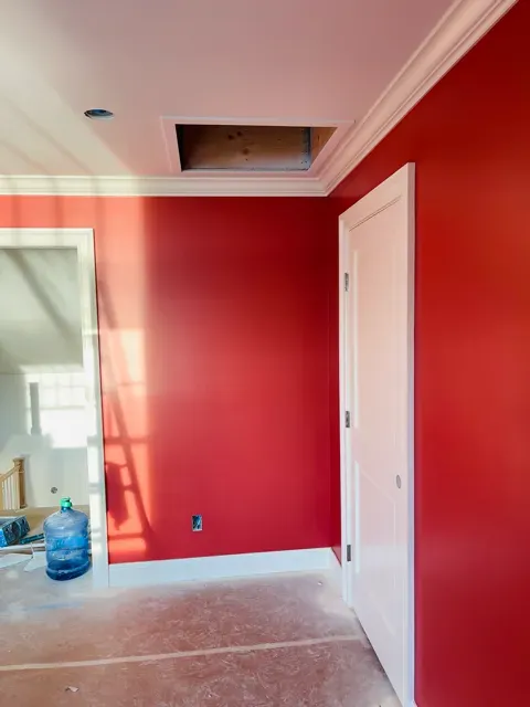 Interior room with freshly painted red wall, white trim, and a door, showcasing professional painting quality by Victory Painting LLC.