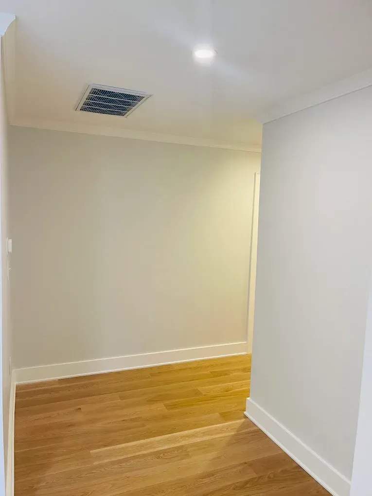 Interior hallway with freshly painted light-colored walls and polished wooden flooring, showcasing clean lines and modern finishes, relevant to professional painting services by Victory Painting LLC.