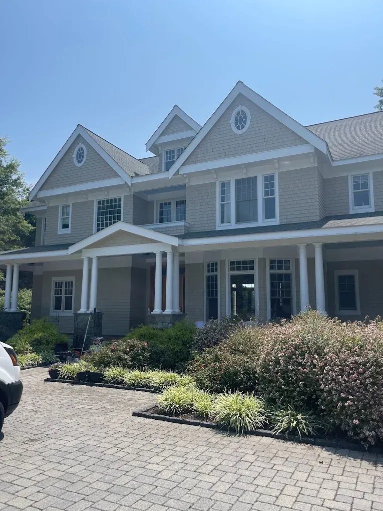 Newly built home showcasing professional exterior painting, elegant architectural details, and landscaped garden, emphasizing high-quality finishes and curb appeal.