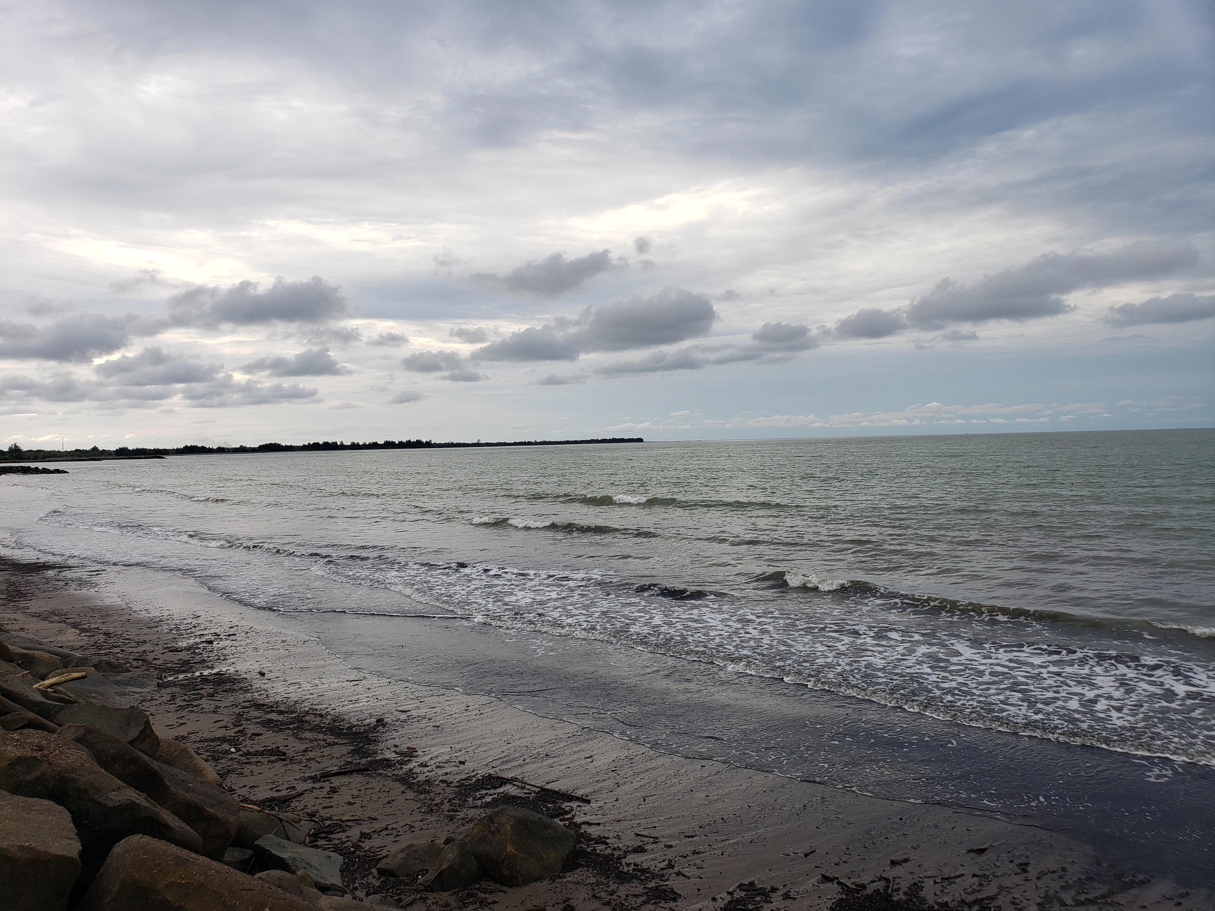 Calm overcast shoreline with soft gray clouds gathering in the distance